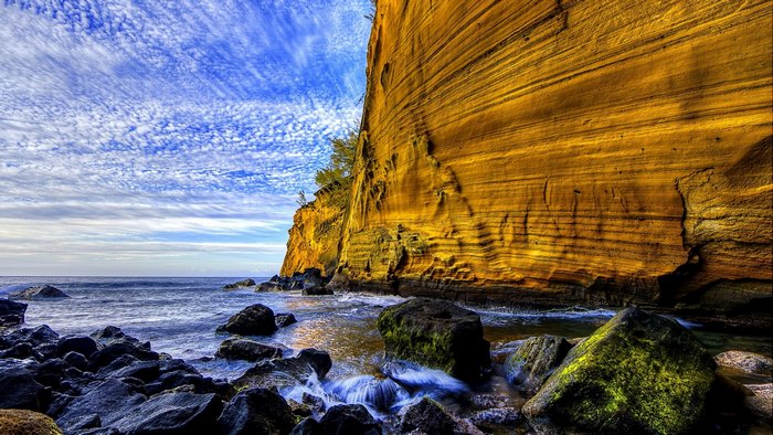 Ocean waves crash against a rocky cliff face
