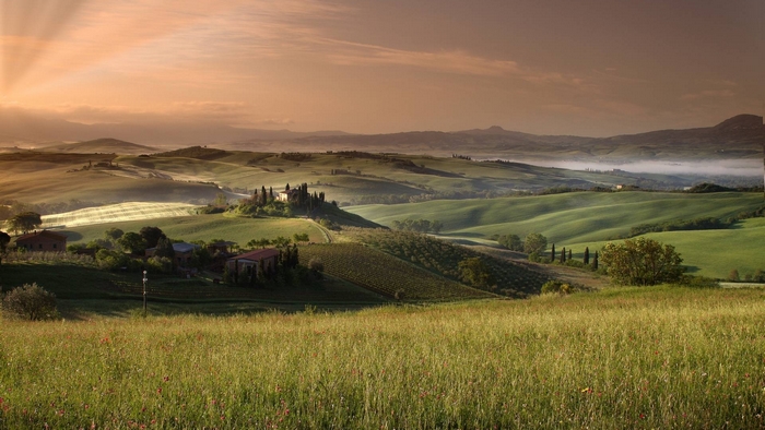 Tuscan landscape with rolling hills and farmhouses at sunrise