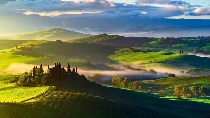 Rolling green hills with fog and a villa