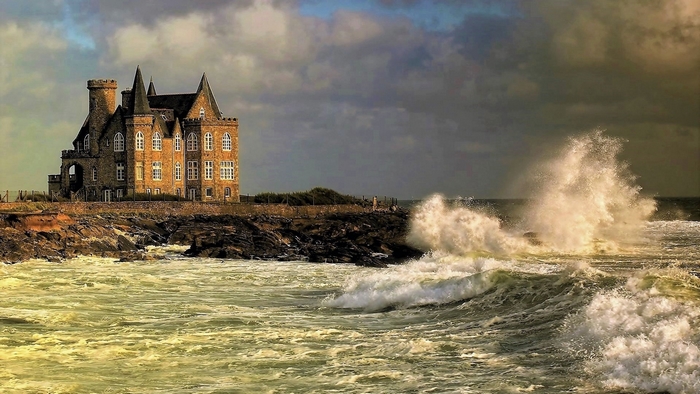 Castle on the rocky coast with crashing waves
