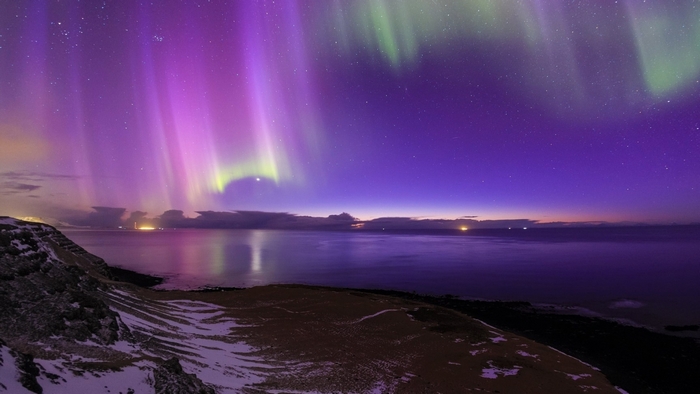 Aurora Borealis over the ocean and snowy coast