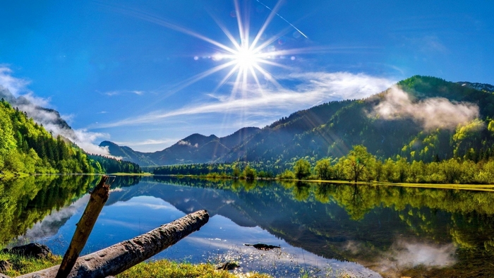 Sun shining over a mountain lake with forest