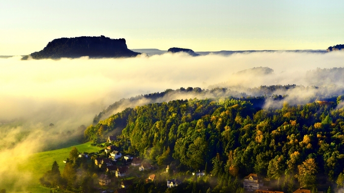 Misty mountain landscape with forest and houses