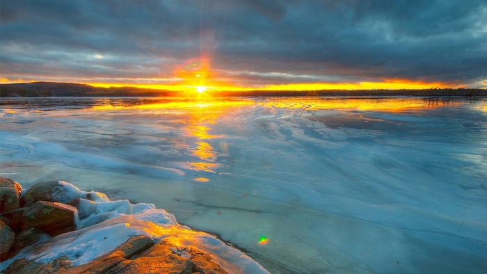 Sunset over a frozen lake with rocky shore