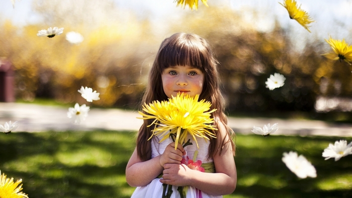Young girl holding yellow flowers with white flowers falling