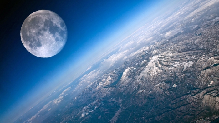 The Moon over Earth's mountains and clouds