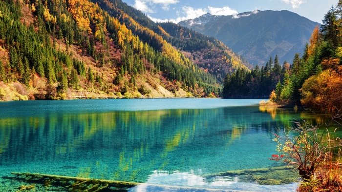 Turquoise lake surrounded by autumn forest and mountains