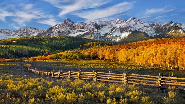 Autumn mountains with a wooden fence in a field