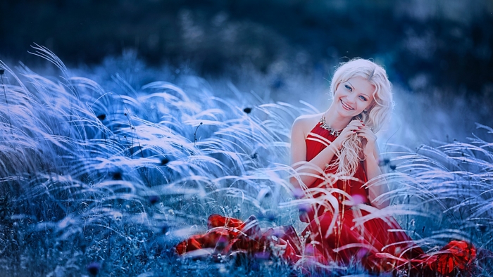 Woman in red dress sitting in a field of grass