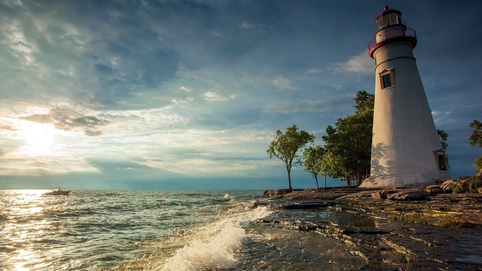 Lighthouse on a rocky shore with a boat on the sea