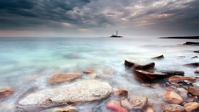 Lighthouse on a rocky shore with stormy clouds