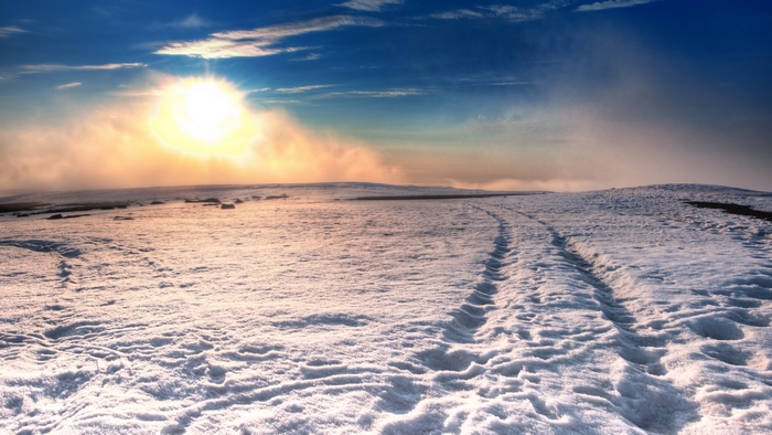 Sunlight over a snowy landscape with tire tracks