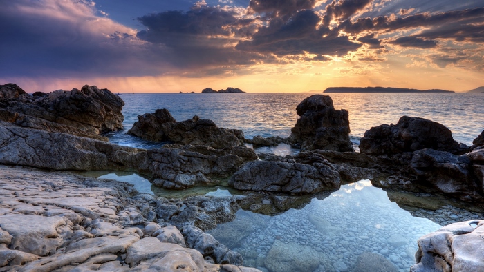 Calm Rocky Shore at Sunset with Serene Reflections