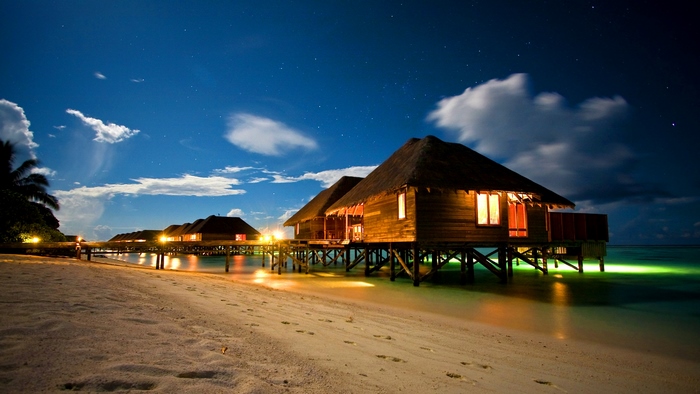 Overwater bungalows at night on a beach