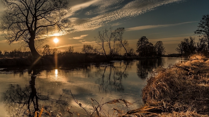 Sunset over a river with trees and reflections