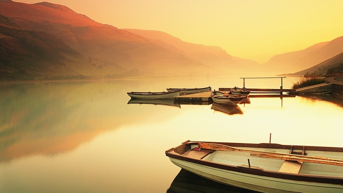 Boats on a lake at sunset with mountains