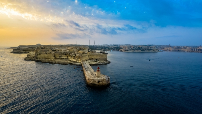 Mediterranean Lighthouse at Sunrise Over Calm Harbor