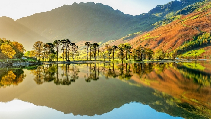 Trees reflecting in a lake with mountains in the background