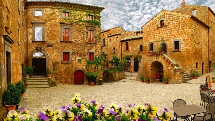 Italian village square with stone buildings and flowers
