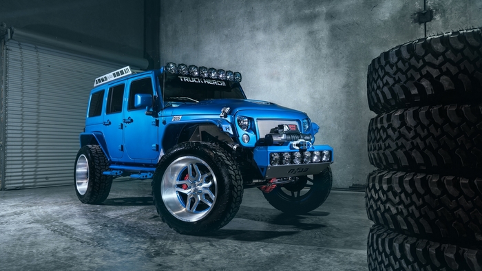 Blue Jeep Wrangler with large tires and lights