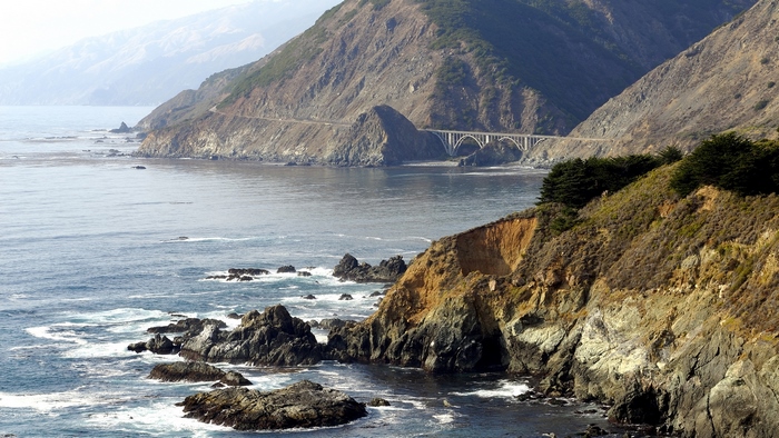 Coastal highway bridge over the ocean with rocky cliffs
