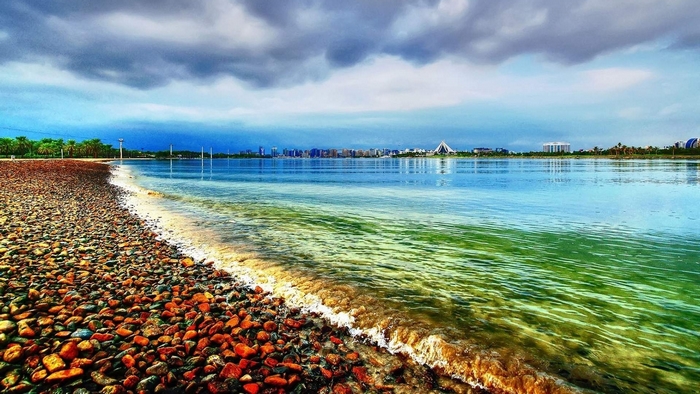 Pebble beach with calm water and city skyline