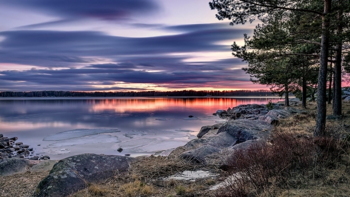 Sunset over a lake with trees and rocks