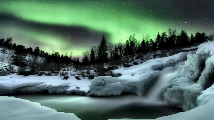 Aurora Borealis over a frozen waterfall in winter