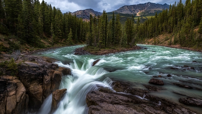 Waterfall in a Canadian forest with mountains