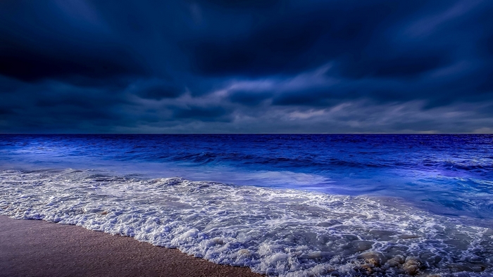 Dark clouds over a blue ocean at dusk