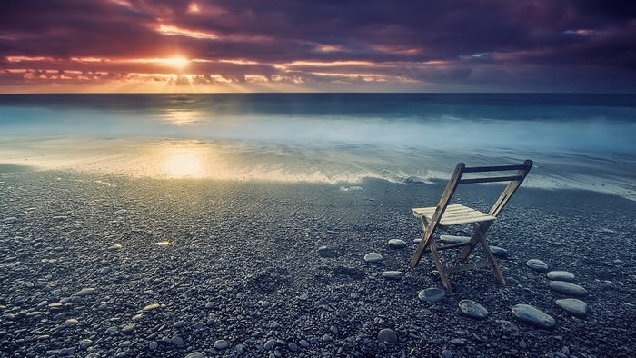 Chair on a rocky beach at sunset by the sea