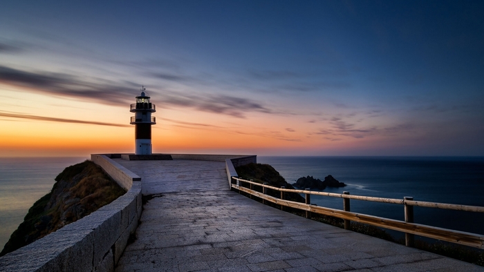 Lighthouse on a cliff overlooking the sea at sunset