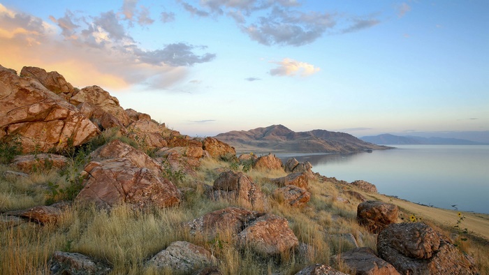 Rocky shore overlooking a calm lake and distant mountains