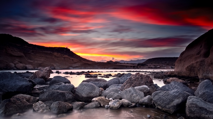 Rocky coastline at sunset with colorful clouds over the sea