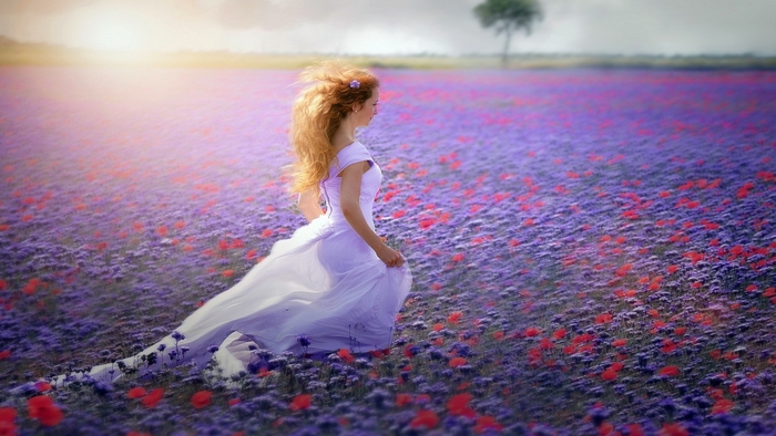 Woman in Flowing White Dress Running Through Flower Field