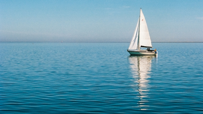Sailboat on a calm blue sea under a clear sky