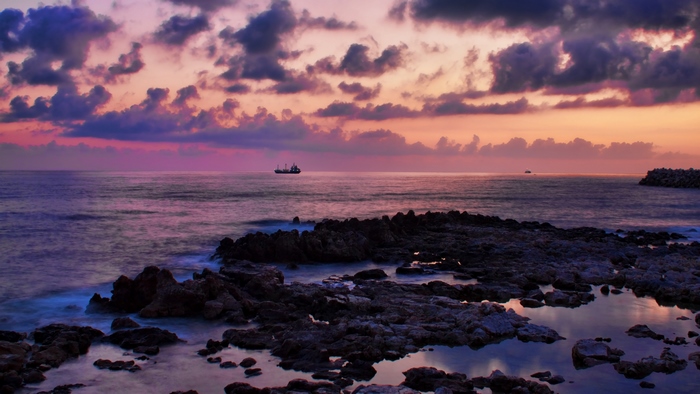 Ship on the sea during sunset with purple clouds