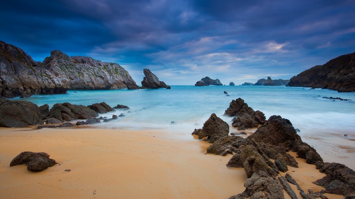 Rocky beach with turquoise water and dramatic sky