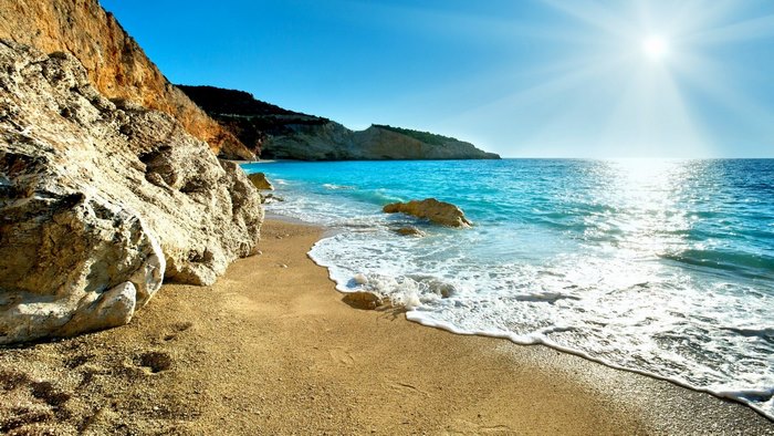 Beach with turquoise water and rocky cliffs under the sun