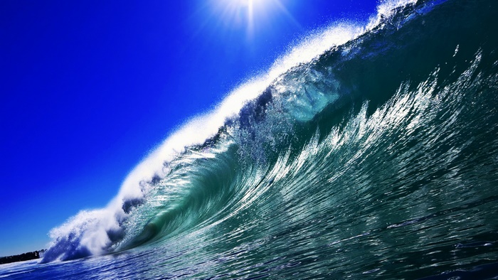 Sun shining over a powerful ocean wave