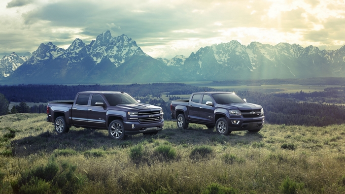 Two Chevrolet trucks in front of mountains