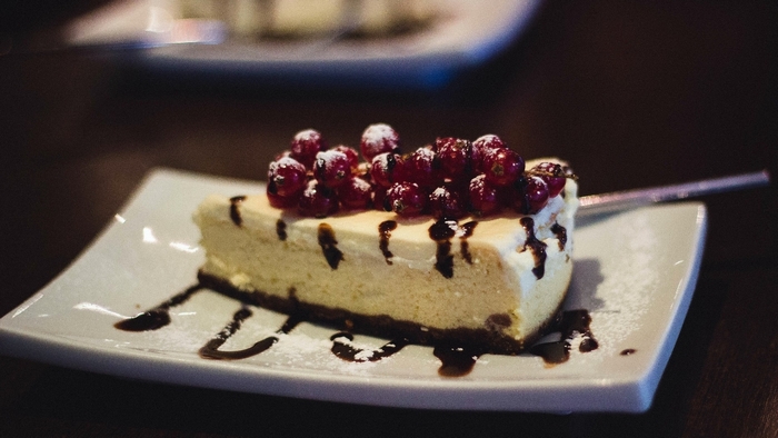Slice of cheesecake with berries and chocolate drizzle
