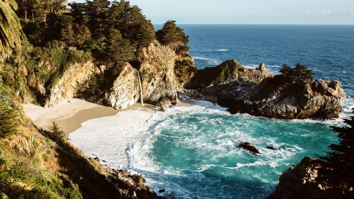 Waterfall cascading onto a sandy beach in Big Sur, California