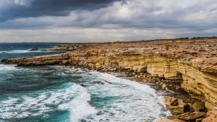 Rocky coastline with crashing waves under a cloudy sky