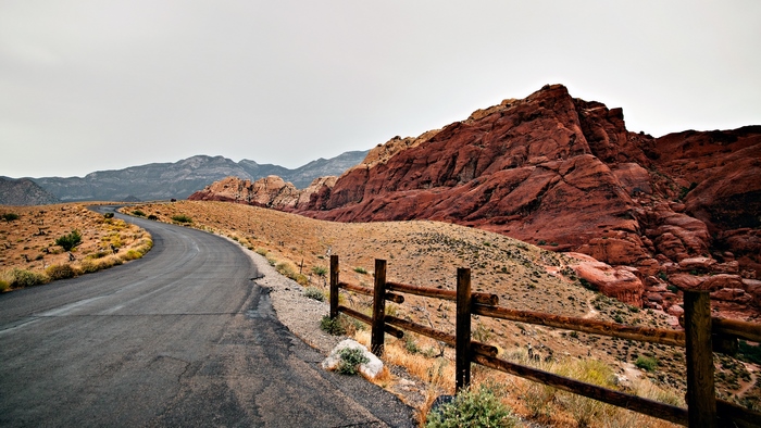 Desert road with red rock mountains and wooden fence