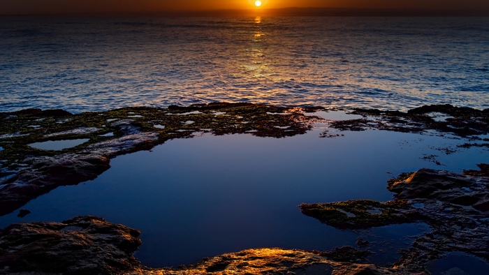 Sunset over the ocean with rock pools