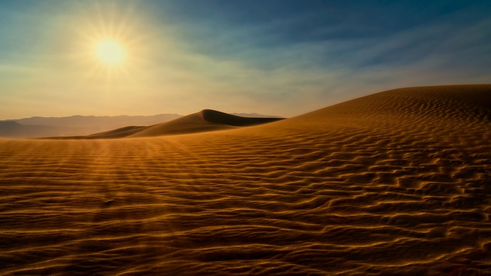 Sunlight over sand dunes in Death Valley at sunset