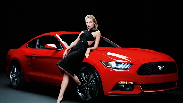 Blonde woman leaning on a red Ford Mustang