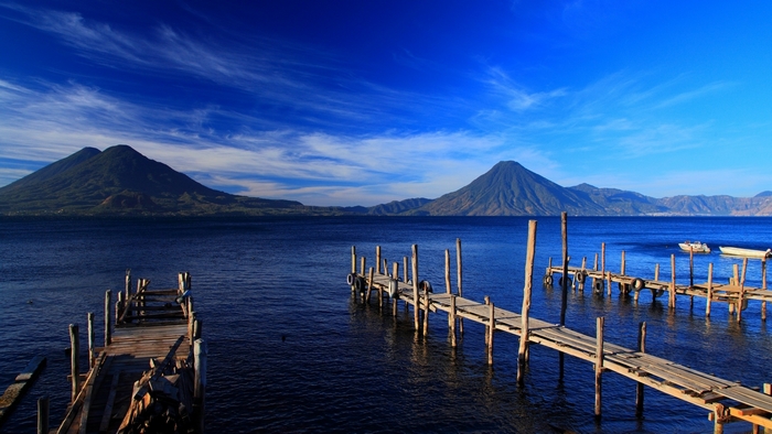 Wooden piers on a deep blue lake with volcanoes in the background