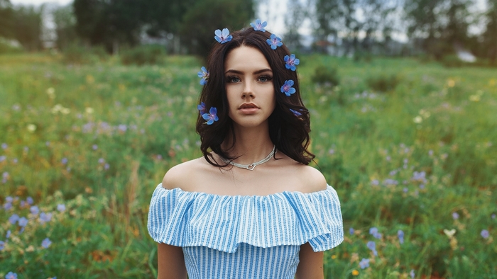 Young woman with blue flowers in her hair in a field